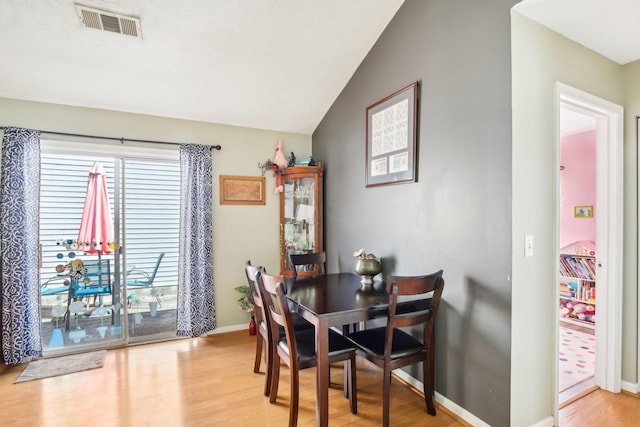 dining space featuring vaulted ceiling, baseboards, visible vents, and light wood-style floors