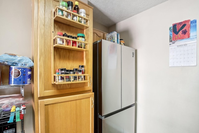 interior space featuring freestanding refrigerator, light brown cabinets, a textured ceiling, and open shelves