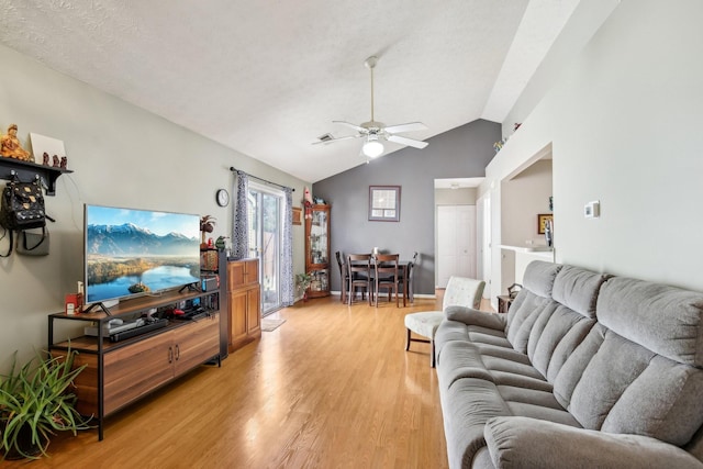 living area featuring light wood-type flooring, visible vents, a ceiling fan, and lofted ceiling