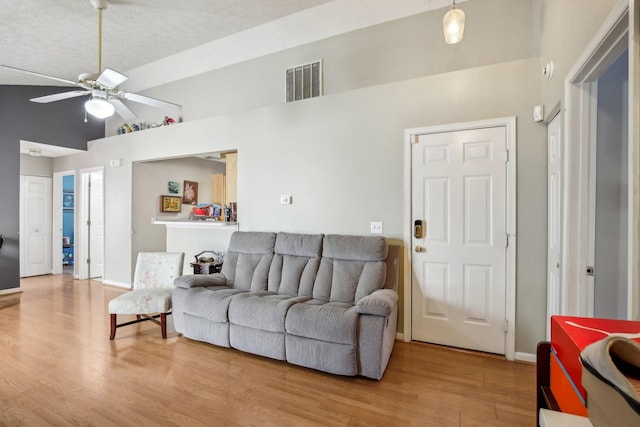 living room featuring baseboards, visible vents, a ceiling fan, lofted ceiling, and wood finished floors