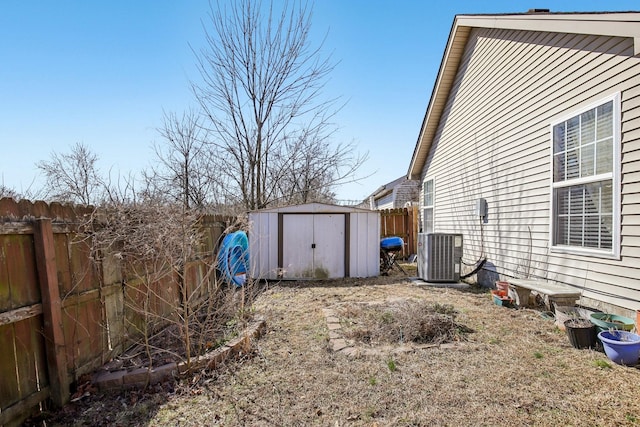 view of yard with a storage shed, a fenced backyard, cooling unit, and an outdoor structure