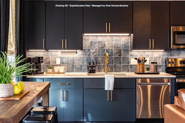 kitchen with modern cabinets, appliances with stainless steel finishes, decorative backsplash, and a sink