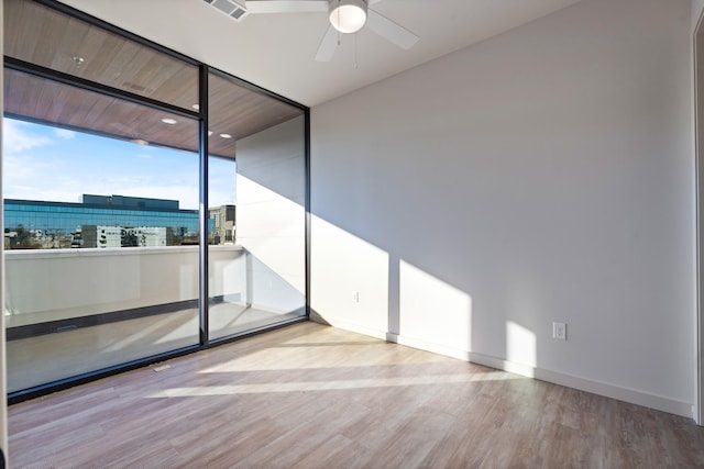 empty room featuring a ceiling fan, light wood-type flooring, visible vents, and baseboards