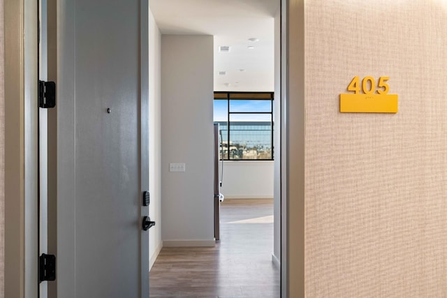 corridor featuring baseboards, visible vents, and light wood finished floors