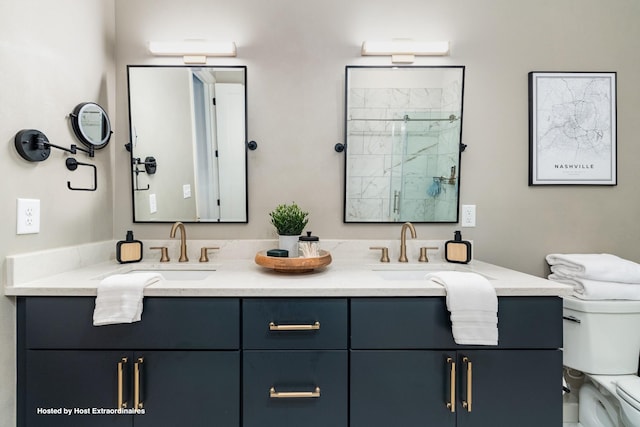 bathroom featuring double vanity, a stall shower, a sink, and toilet