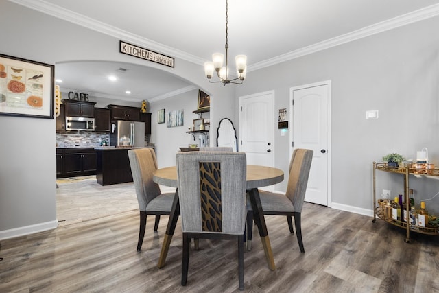 dining room with arched walkways, a notable chandelier, wood finished floors, and baseboards