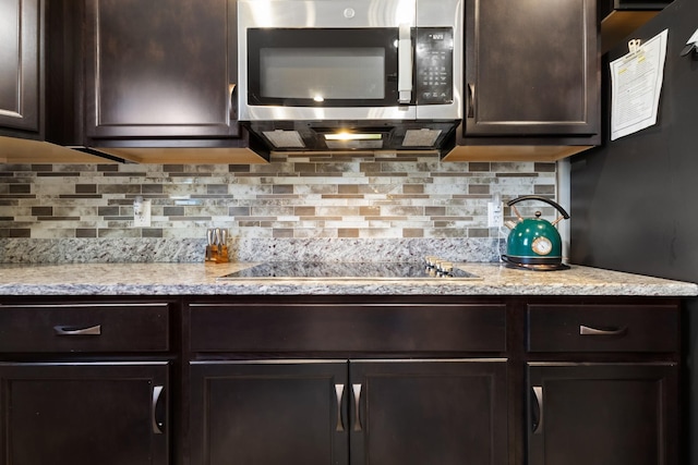 kitchen with tasteful backsplash, stainless steel microwave, dark brown cabinets, and black electric cooktop