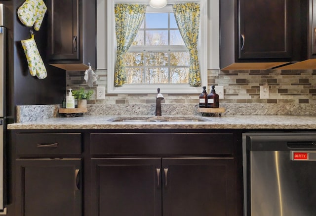 kitchen with a sink, light countertops, stainless steel dishwasher, dark brown cabinets, and backsplash