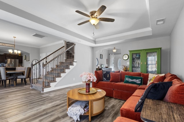 living room featuring arched walkways, stairway, wood finished floors, and visible vents