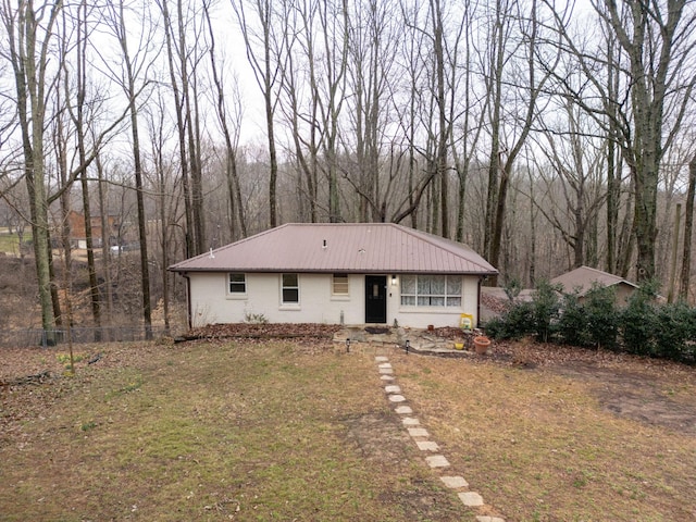 view of front of house featuring metal roof, brick siding, a front yard, and fence