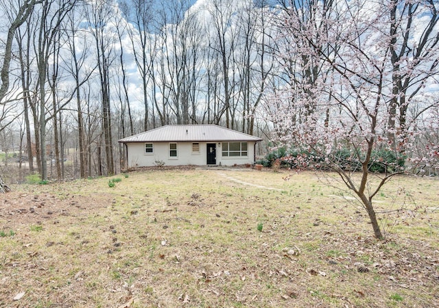 rear view of property featuring metal roof and a yard