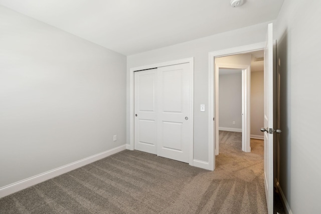 unfurnished bedroom with a closet, carpet, and baseboards