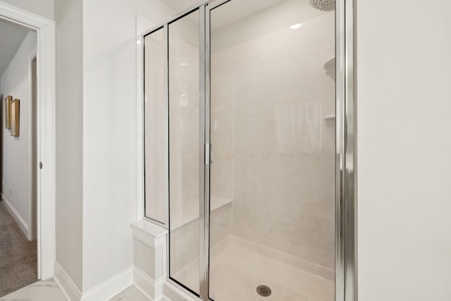 full bath featuring marble finish floor, a shower stall, and baseboards