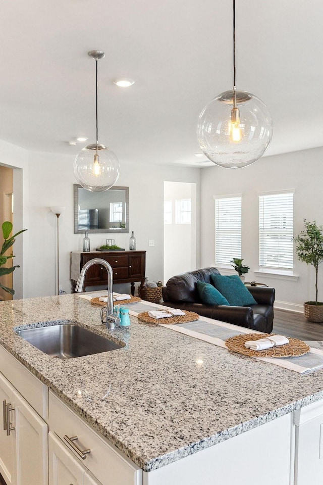 kitchen with open floor plan, a sink, white cabinets, and pendant lighting