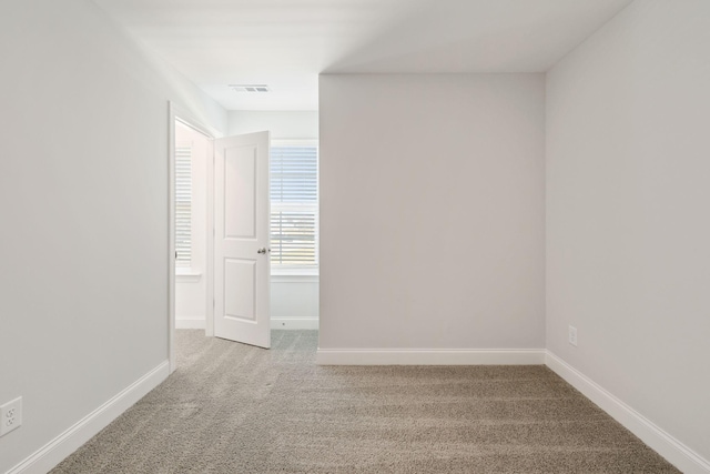 unfurnished room with carpet flooring, visible vents, and baseboards