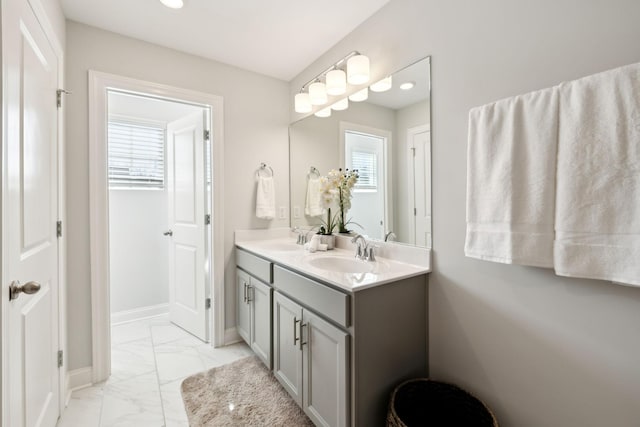 full bathroom with marble finish floor, a sink, baseboards, and double vanity