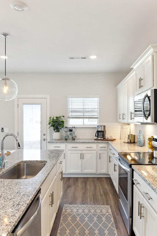 kitchen featuring pendant lighting, tasteful backsplash, appliances with stainless steel finishes, white cabinets, and a sink