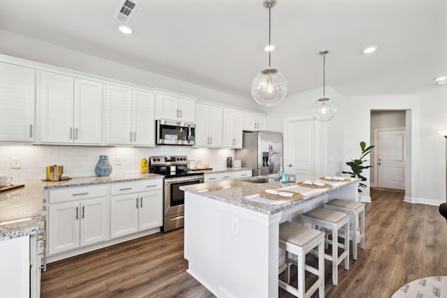 kitchen featuring hanging light fixtures, a kitchen island with sink, appliances with stainless steel finishes, and white cabinets