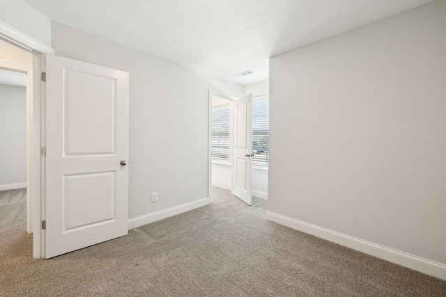 spare room featuring baseboards, visible vents, and light colored carpet