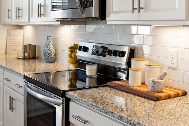 kitchen with appliances with stainless steel finishes, backsplash, and white cabinets