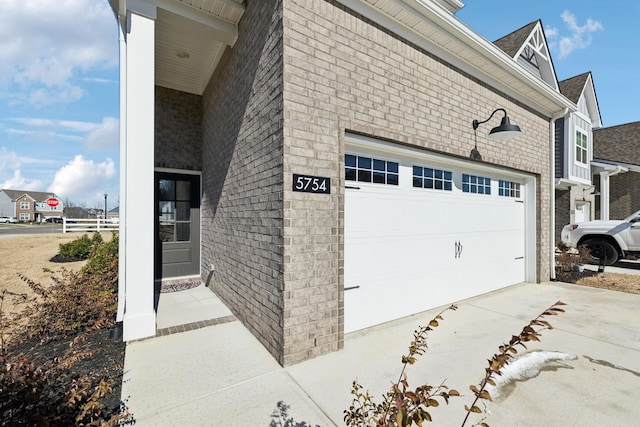 view of side of home featuring brick siding, driveway, an attached garage, and fence