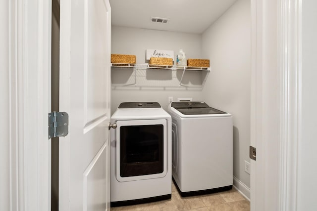 clothes washing area with laundry area, washing machine and dryer, and visible vents