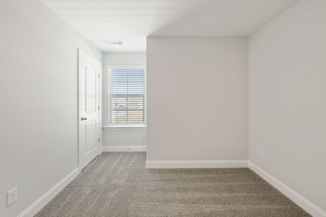 unfurnished room with carpet, visible vents, and baseboards