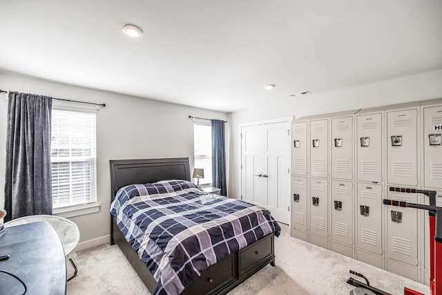 bedroom with light carpet, baseboards, and multiple windows