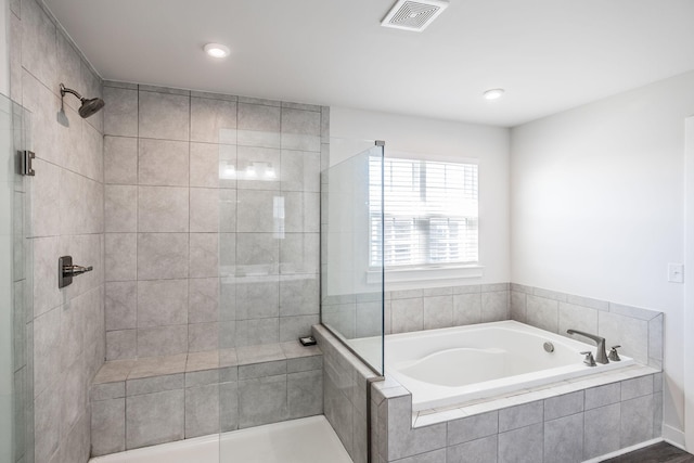 full bathroom with a bath, a tile shower, and visible vents