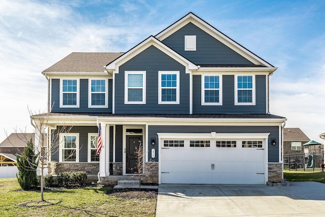 craftsman-style home featuring driveway, stone siding, an attached garage, and a front yard