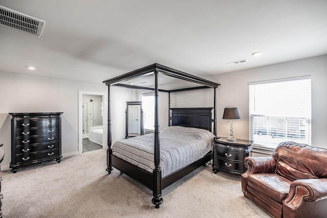 bedroom featuring ensuite bath, visible vents, and light colored carpet