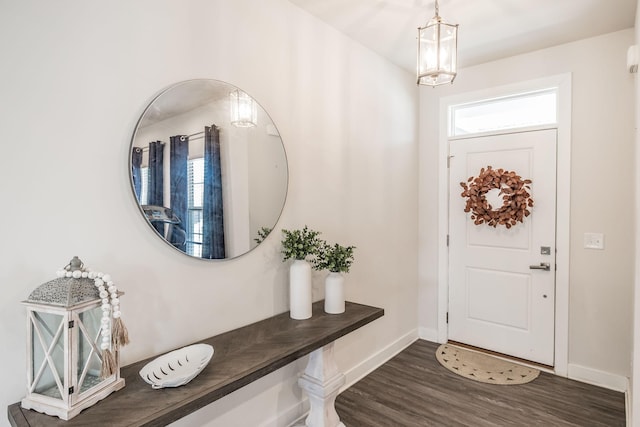 entryway with a notable chandelier, dark wood-style flooring, and baseboards