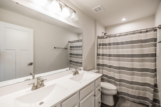 full bath featuring visible vents, a sink, toilet, and double vanity