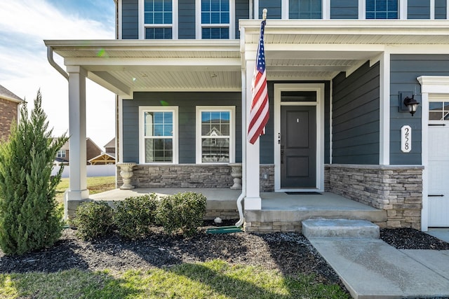 doorway to property featuring stone siding and covered porch