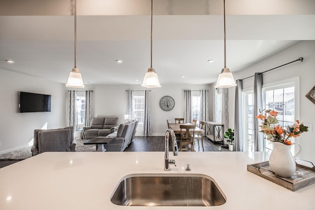 kitchen featuring a sink, a healthy amount of sunlight, open floor plan, hanging light fixtures, and light countertops