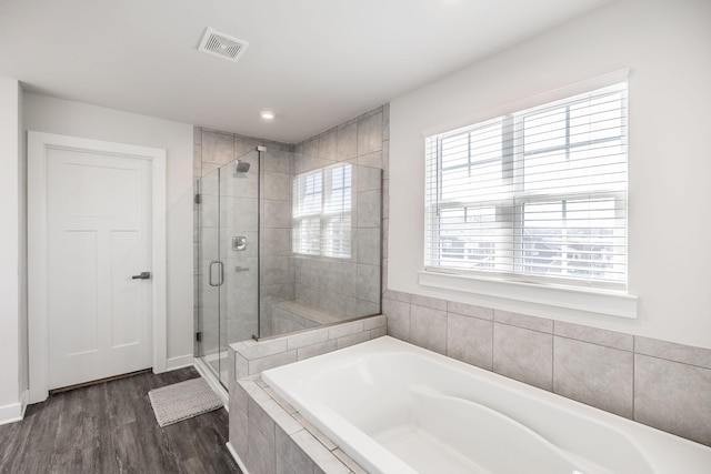 full bathroom featuring a shower stall, visible vents, a bath, and wood finished floors