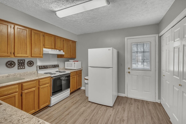 kitchen with white appliances, light wood finished floors, brown cabinets, light countertops, and under cabinet range hood