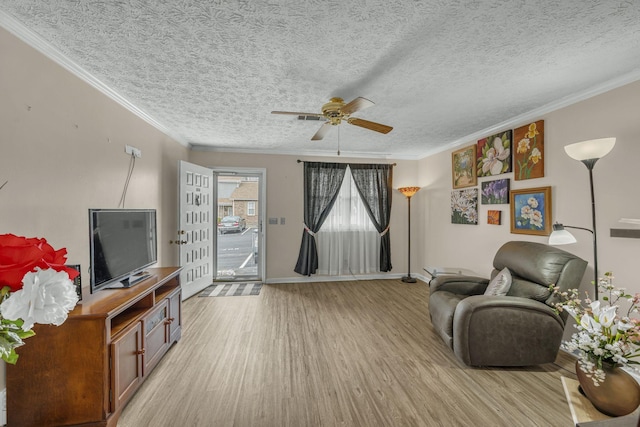 sitting room with ornamental molding, light wood-type flooring, a textured ceiling, and baseboards