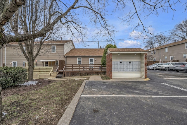 view of front of property featuring uncovered parking, roof with shingles, and a wooden deck