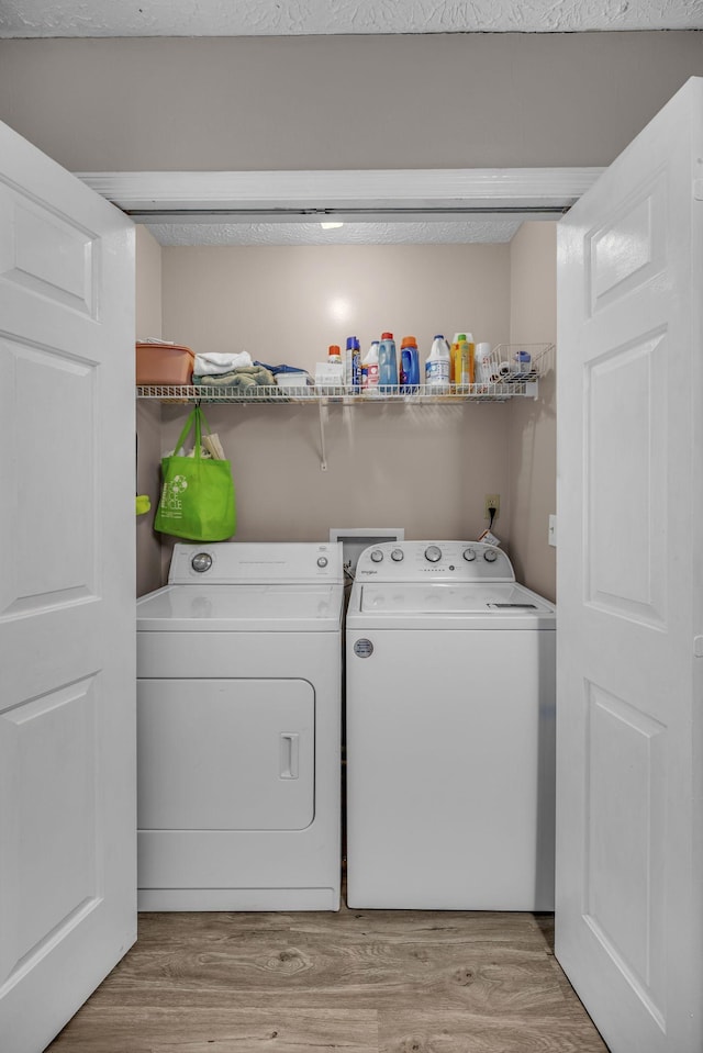 laundry area with laundry area, washer and clothes dryer, and light wood-style floors