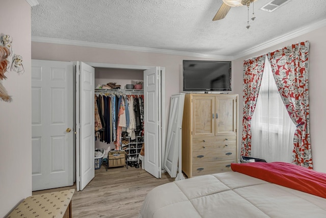 bedroom featuring light wood-style floors, visible vents, crown molding, and a textured ceiling