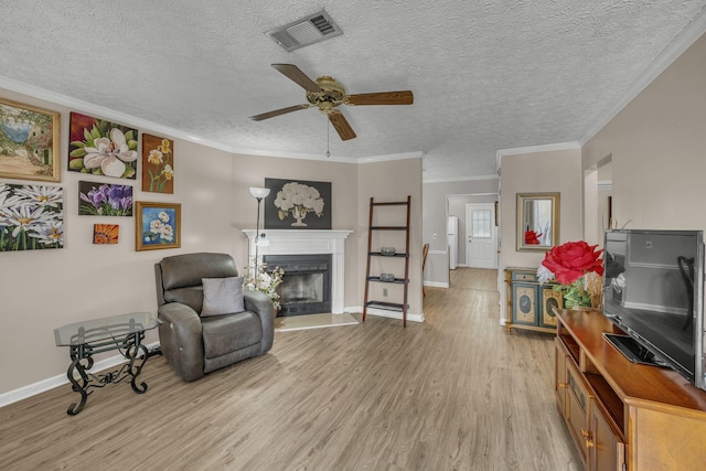 sitting room featuring light wood-type flooring, a fireplace, visible vents, and crown molding