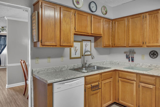 kitchen featuring light wood finished floors, light countertops, white dishwasher, a textured ceiling, and a sink