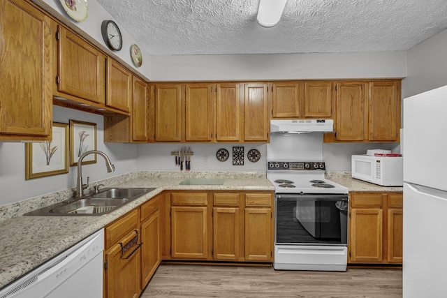 kitchen with light countertops, light wood-style floors, a sink, white appliances, and under cabinet range hood