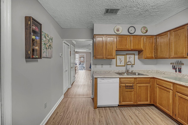 kitchen with light wood-type flooring, visible vents, dishwasher, and a sink