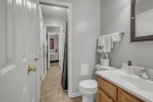 ensuite bathroom featuring connected bathroom, a textured ceiling, toilet, and vanity