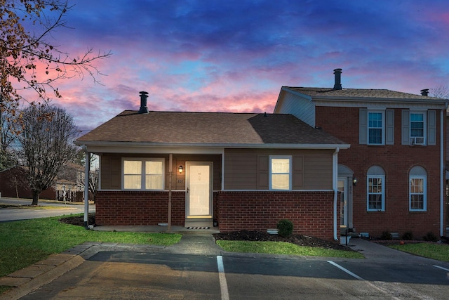 view of front of home featuring uncovered parking, brick siding, roof with shingles, and cooling unit