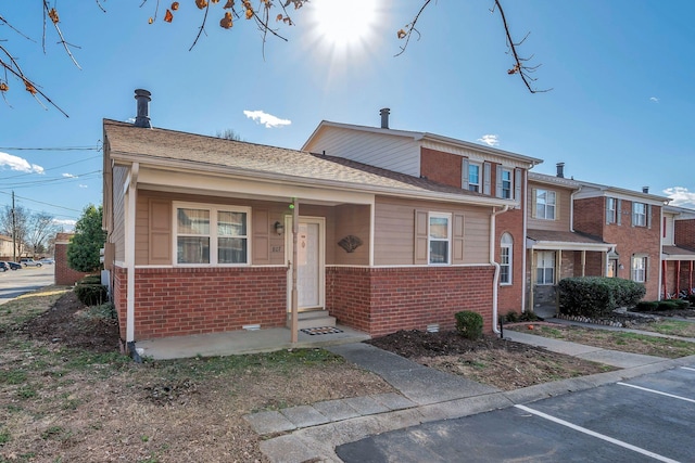 view of front of home with uncovered parking, brick siding, crawl space, and a shingled roof