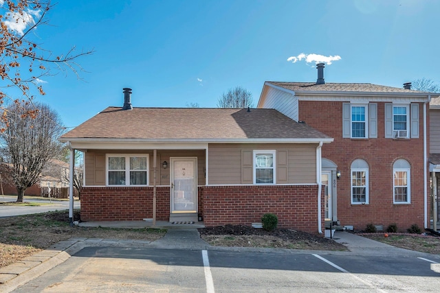 view of front of home with roof with shingles and brick siding