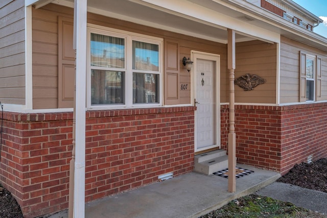 view of exterior entry featuring brick siding